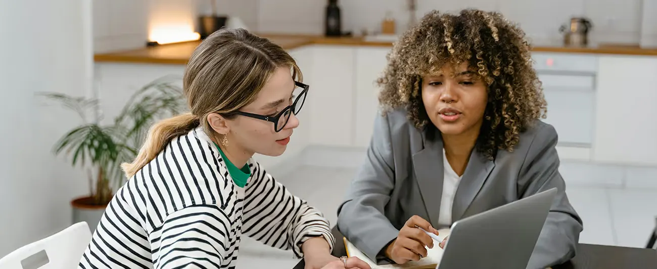 Duas profissionais revisando números da empresa no notebook
